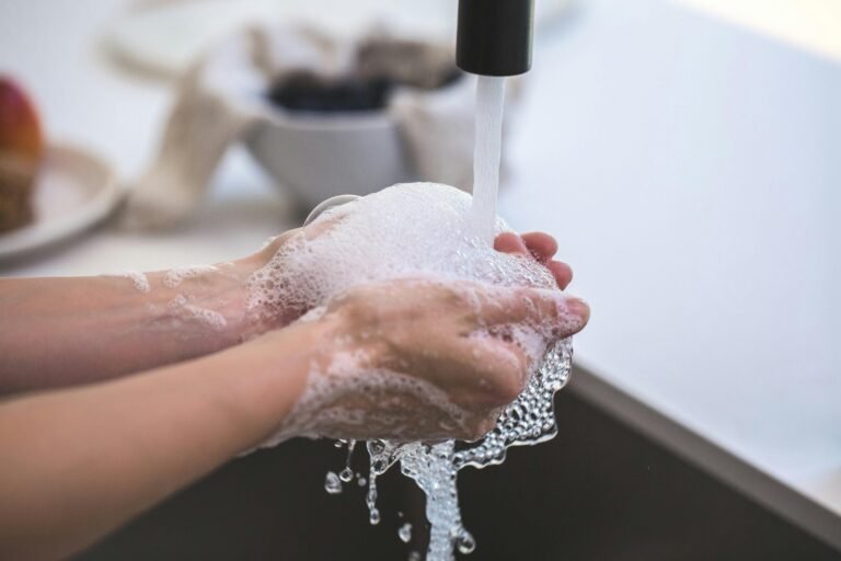 Close-up of hands being washed with foamy soap under a faucet, highlighting hygiene and cleanliness.
