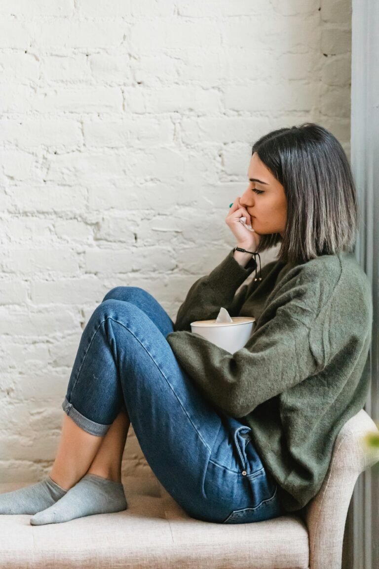 Young woman sitting in a pensive mood with tissues, expressing contemplation and emotion.