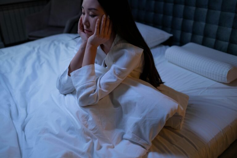 An Asian woman in bed at night, experiencing insomnia and loneliness, deep in thought.